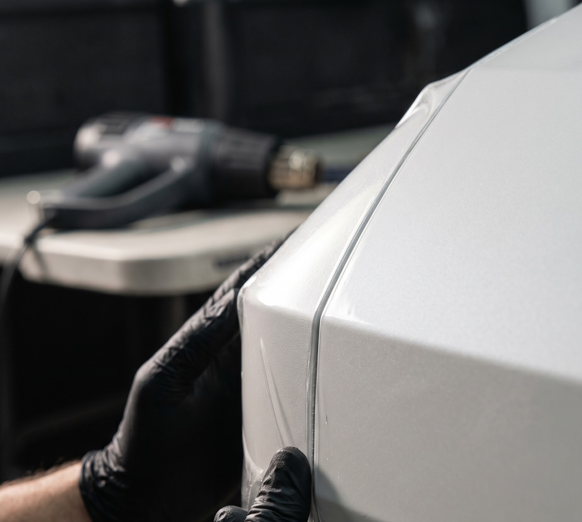 Technician applying paint protection film to a vehicle hood